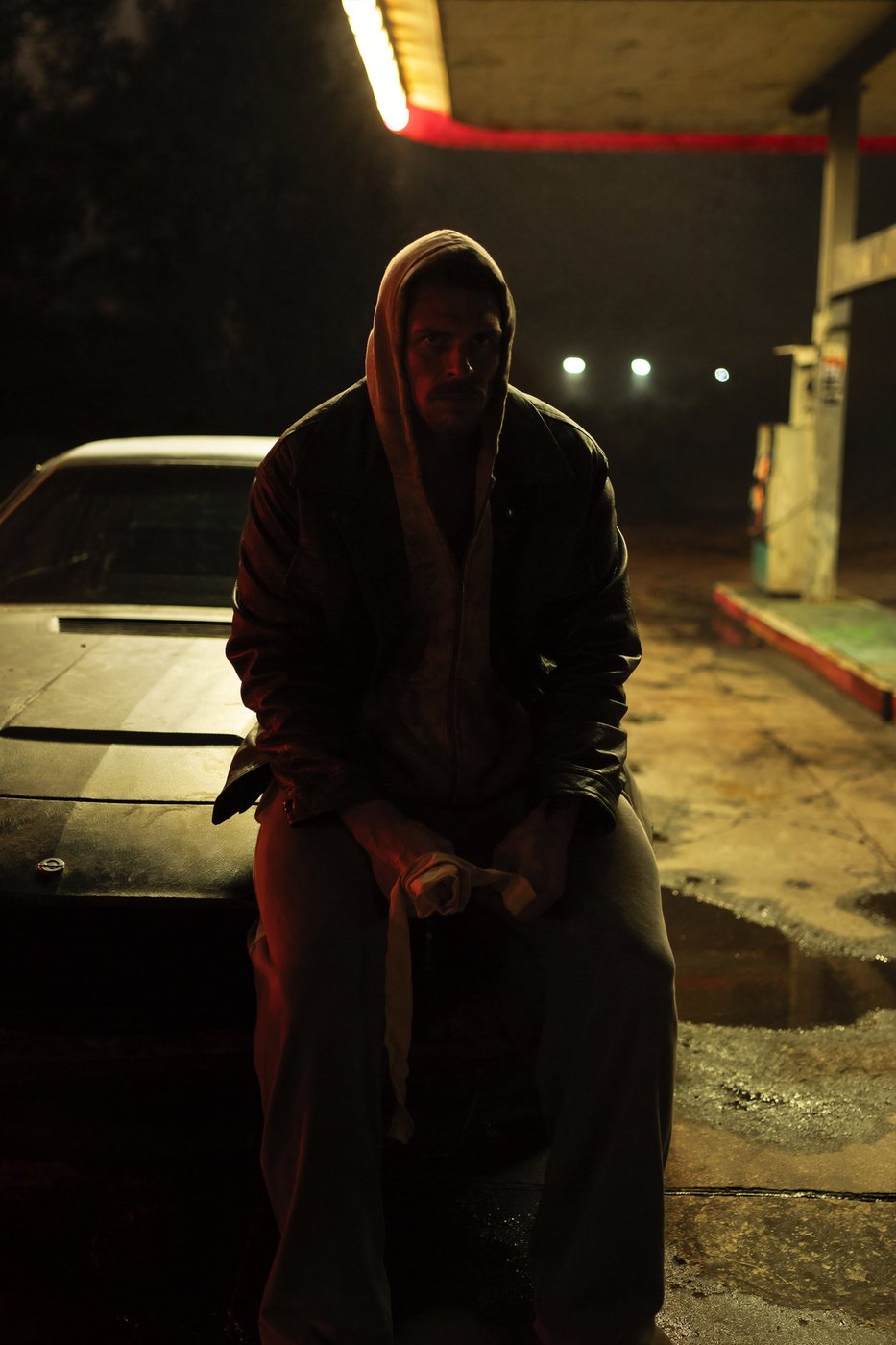 A hooded figure at a petrol station at night